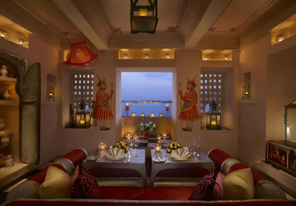 a dining room with a table and chairs and a window at The Leela Palace Udaipur in Udaipur