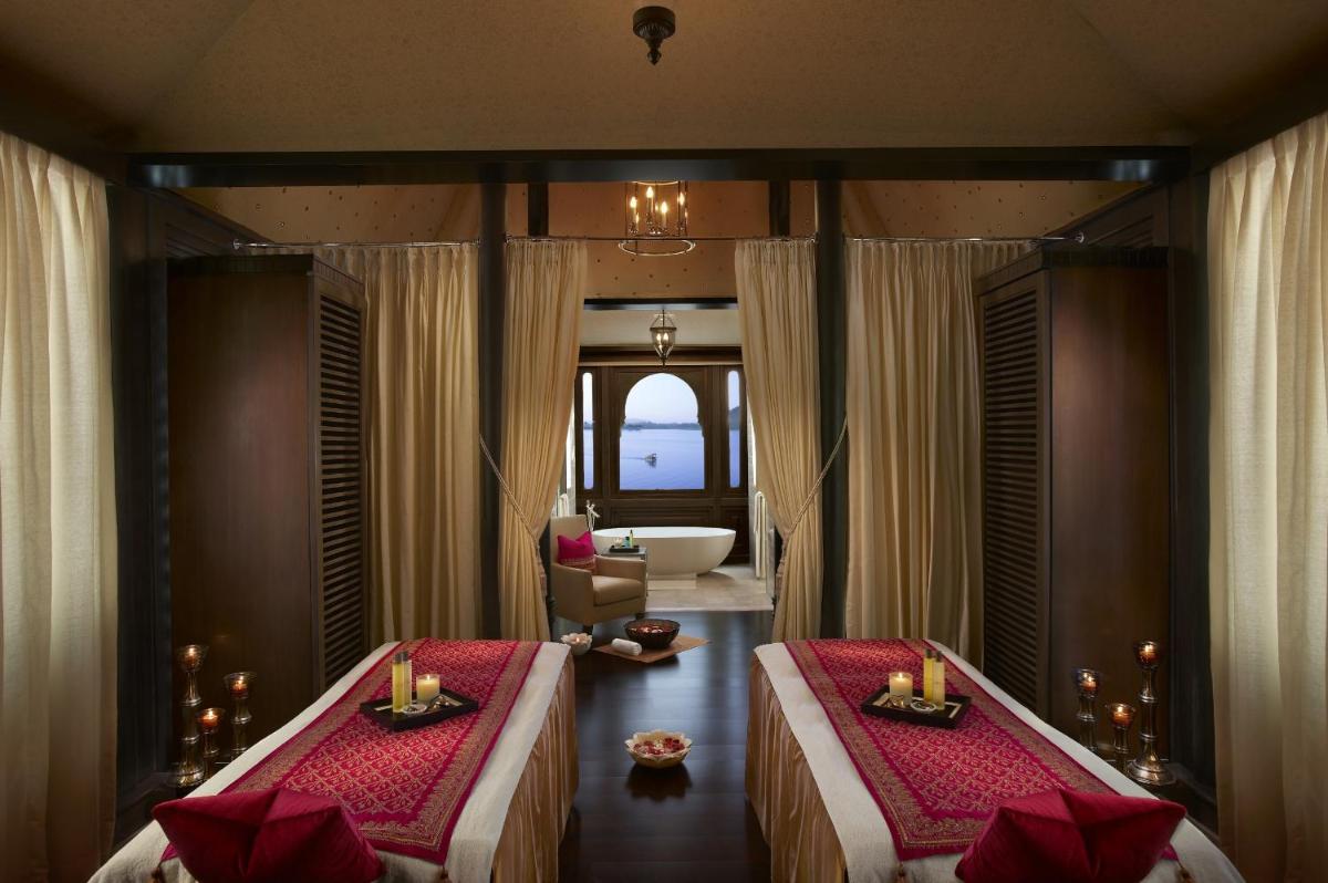 a room with two beds and a bathroom with a tub at The Leela Palace Udaipur in Udaipur