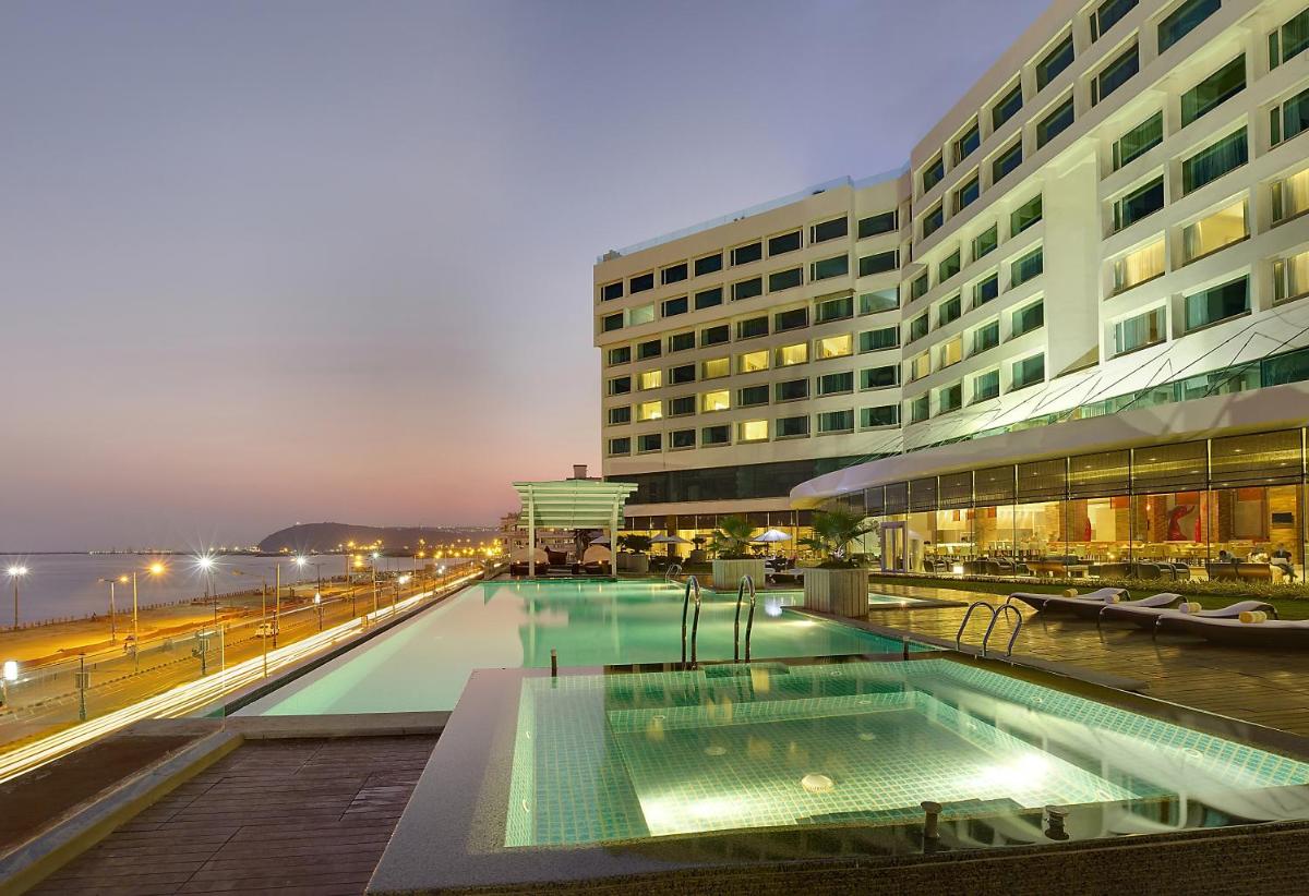 a hotel with a swimming pool in front of a building at Novotel Visakhapatnam Varun Beach in Visakhapatnam