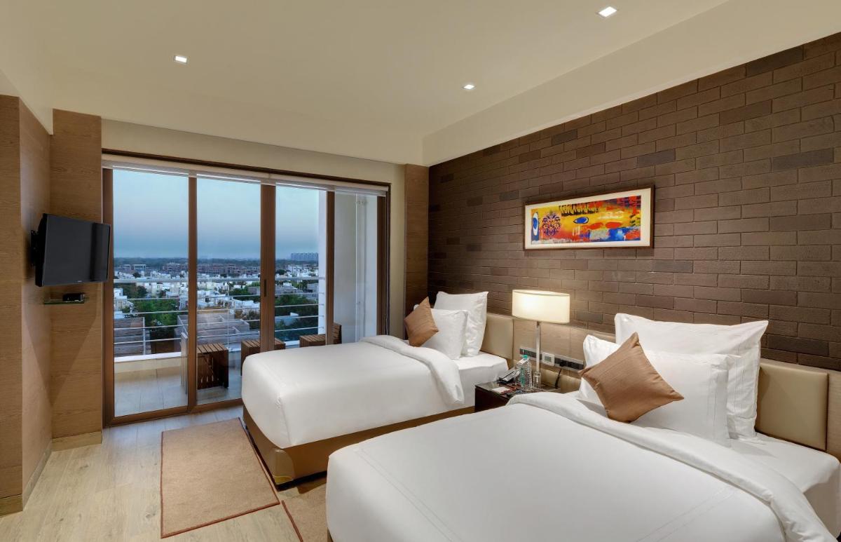 a hotel room with two beds and a window at Wyndham Ahmedabad Shela in Ahmedabad