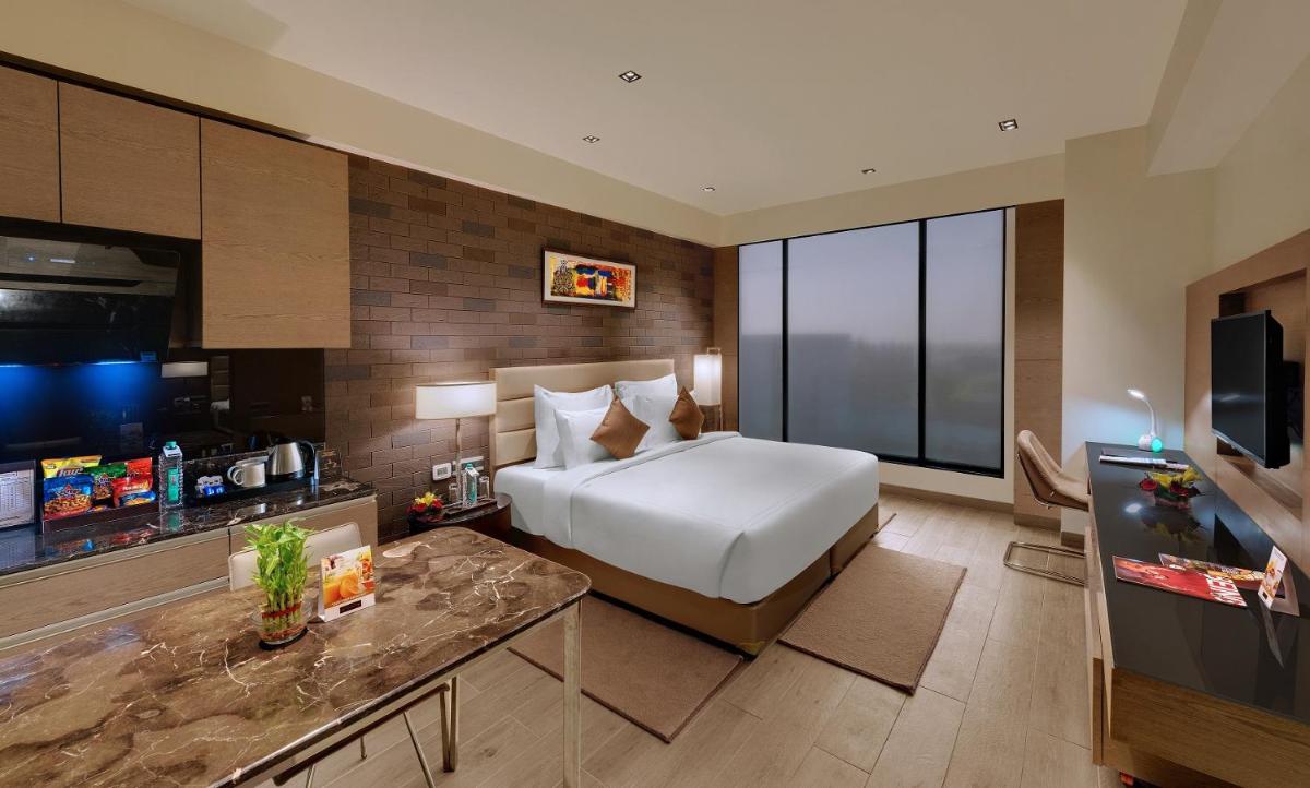 a hotel room with a bed and a television at Wyndham Ahmedabad Shela in Ahmedabad