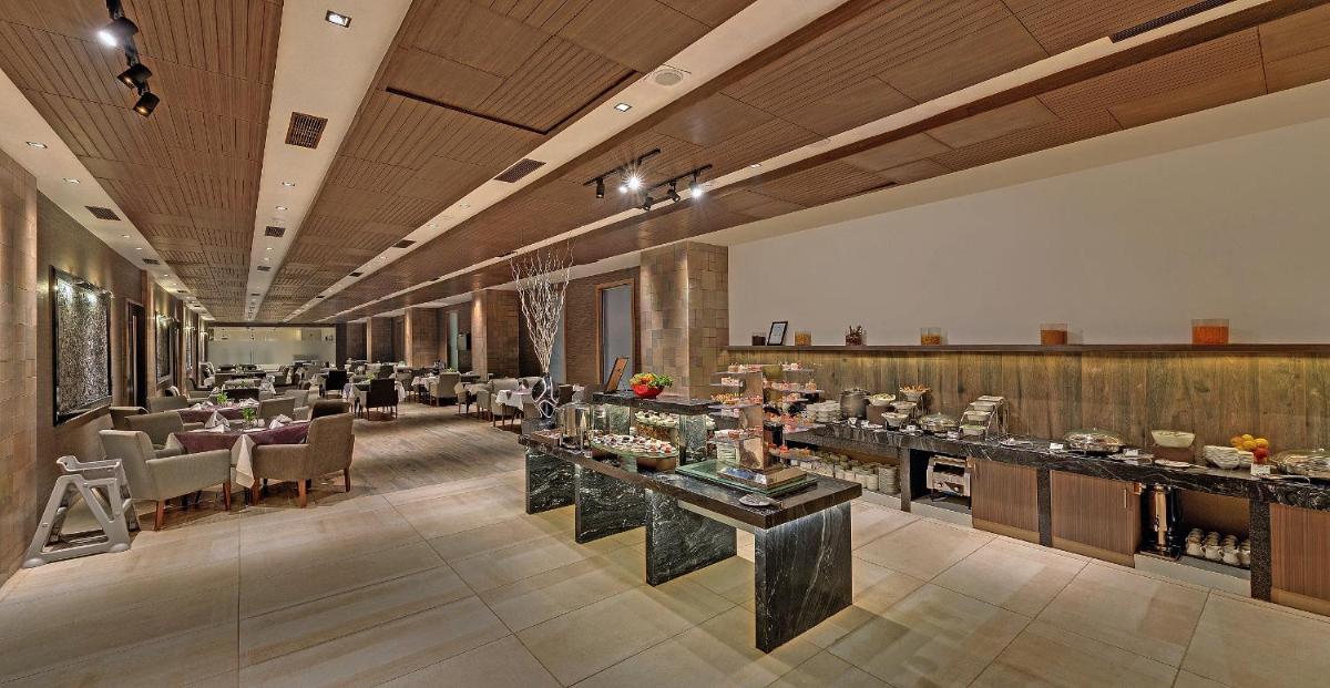 a restaurant with tables and chairs in a large room at Wyndham Ahmedabad Shela in Ahmedabad