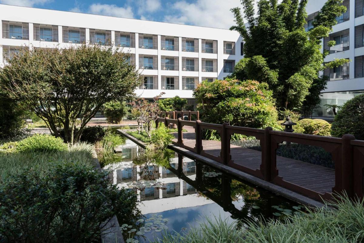 uma ponte sobre um lago em frente a um edifício em Azoris Royal Garden – Leisure & Conference Hotel em Ponta Delgada