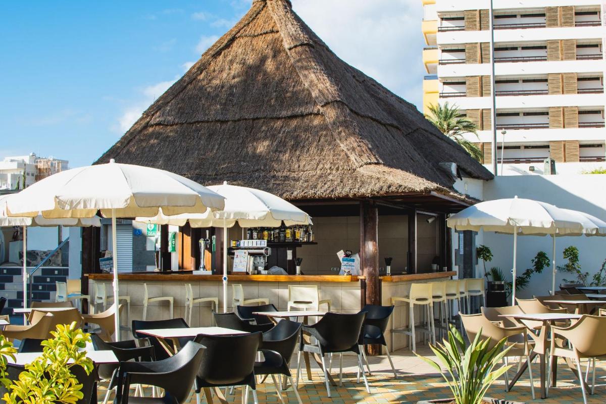 Un restaurante con mesas, sillas y sombrillas. en HL Suitehotel Playa del Inglés - Adults Only, en Playa del Inglés