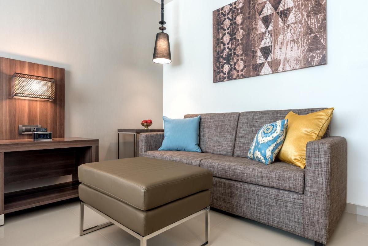 a living room with a couch and a stool at The Residency Towers, Rameswaram in Rāmeswaram