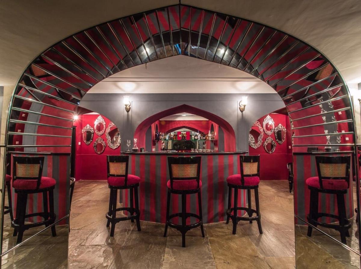 a bar in a room with red walls and red stools at Royal Heritage Haveli - By Leisure Hotels in Jaipur