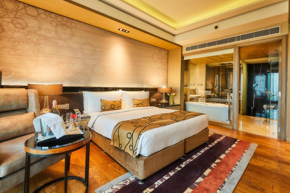 a bedroom with a large bed and a couch at Crowne Plaza New Delhi Rohini by IHG in New Delhi a bedroom with a large bed and a couch at Crowne Plaza New Delhi Rohini by IHG in New Delhi