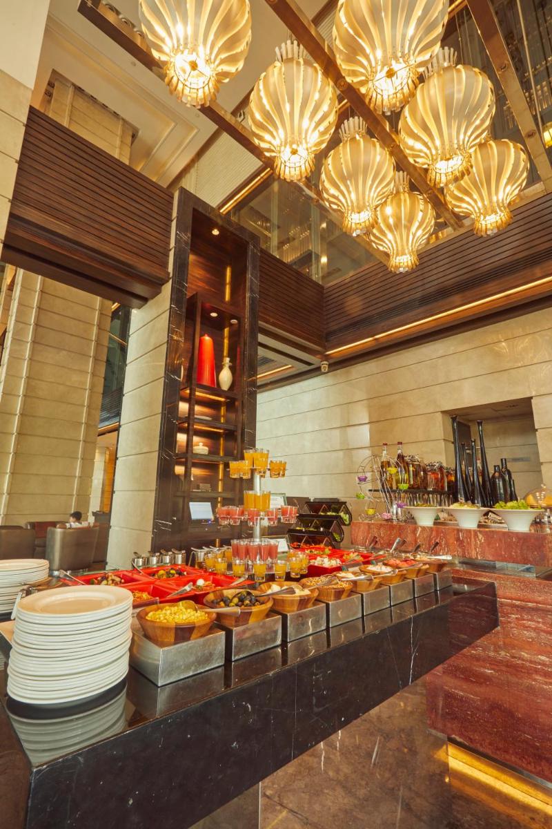 a buffet line with plates and food in a restaurant at Crowne Plaza New Delhi Rohini by IHG in New Delhi a buffet line with plates and food in a restaurant at Crowne Plaza New Delhi Rohini by IHG in New Delhi