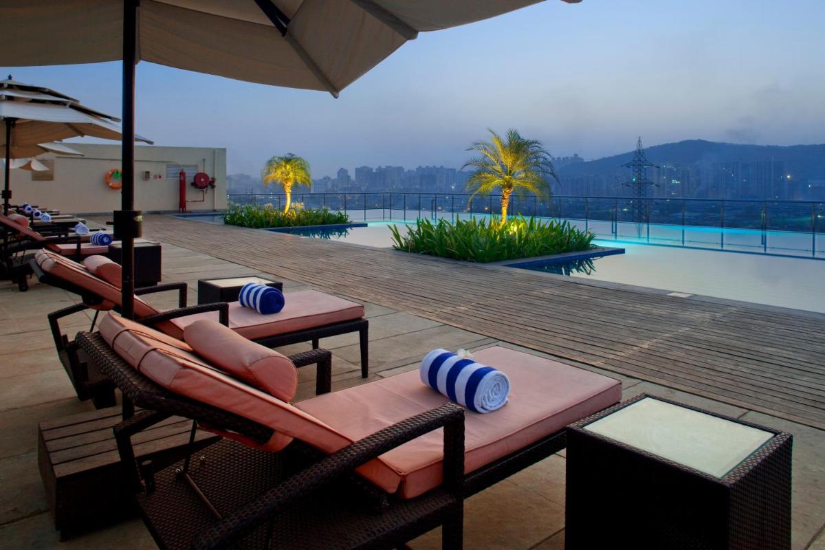 a resort with a pool and chairs and a swimming pool at Holiday Inn Mumbai International Airport by IHG in Mumbai a resort with a pool and chairs and a swimming pool at Holiday Inn Mumbai International Airport by IHG in Mumbai