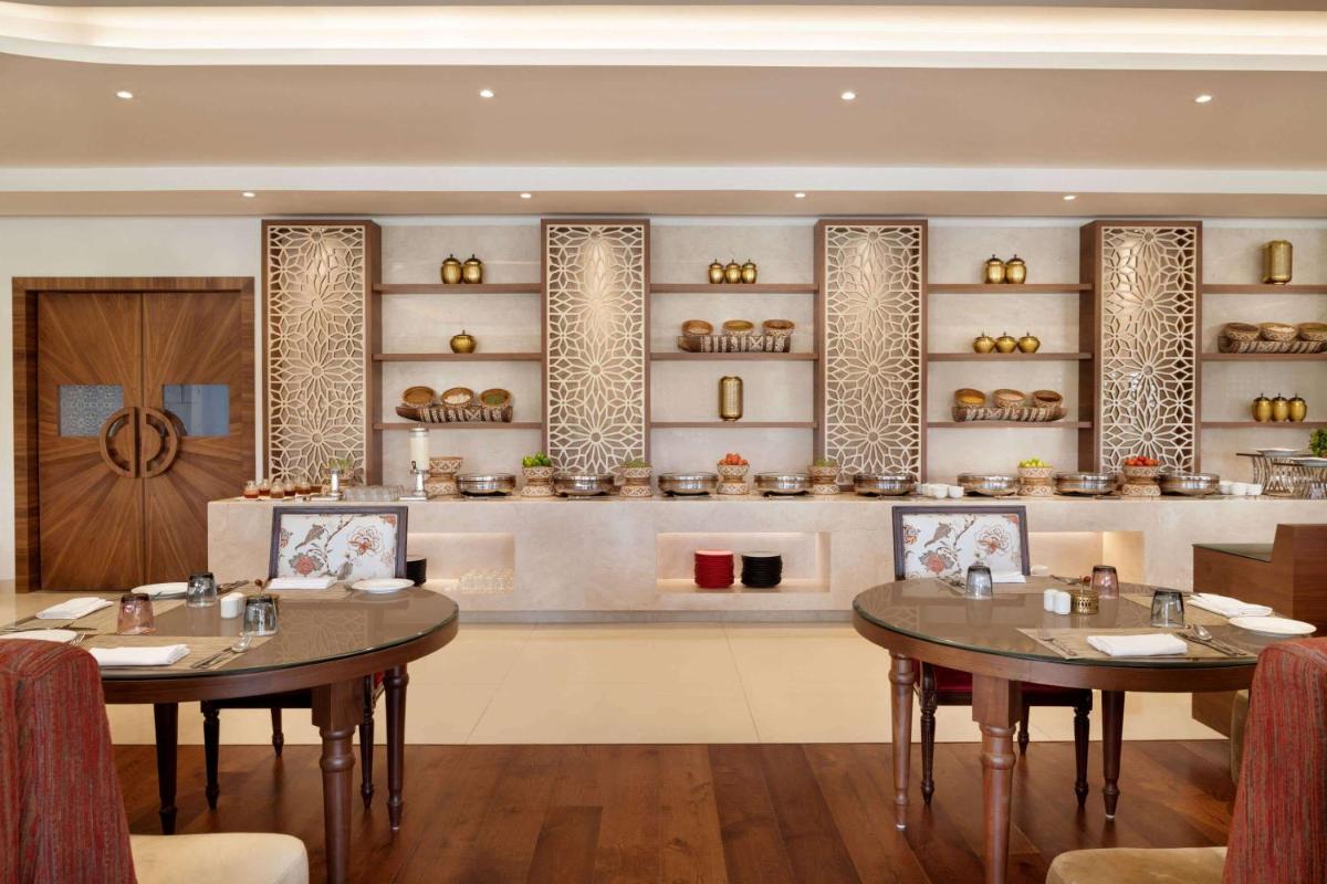 a restaurant with two tables and shelves of food at Hawthorn Suites by Wyndham Dwarka in Dwarka a restaurant with two tables and shelves of food at Hawthorn Suites by Wyndham Dwarka in Dwarka