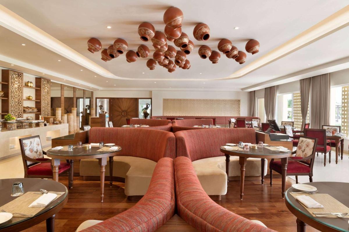 a restaurant with couches and tables in a room at Hawthorn Suites by Wyndham Dwarka in Dwarka a restaurant with couches and tables in a room at Hawthorn Suites by Wyndham Dwarka in Dwarka