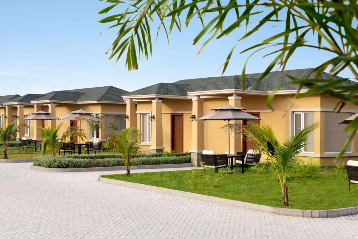 a row of houses with tables and chairs and an umbrella at Hawthorn Suites by Wyndham Dwarka in Dwarka a row of houses with tables and chairs and an umbrella at Hawthorn Suites by Wyndham Dwarka in Dwarka