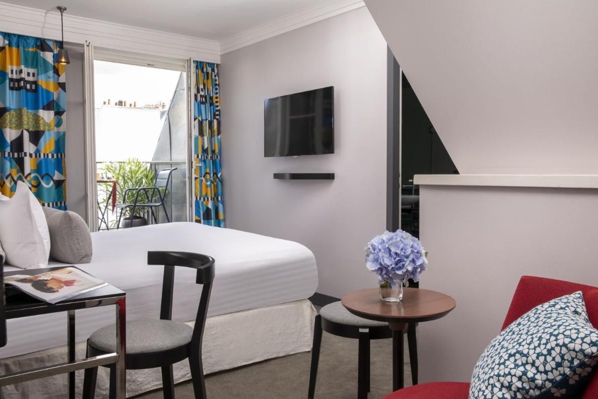 une chambre d'hôtel avec un lit, une table et des chaises dans l'établissement Les Matins de Paris & Spa, à Paris