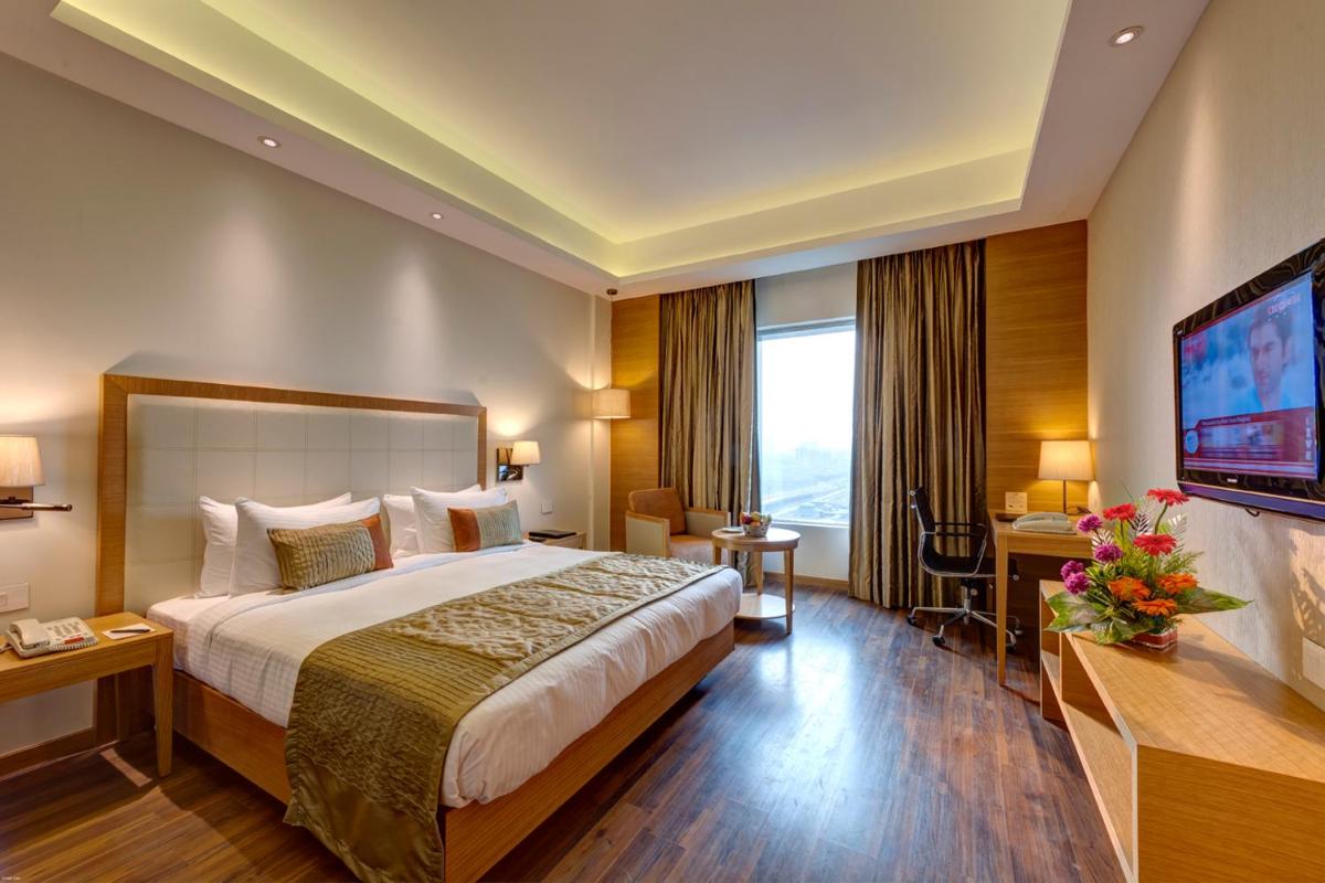 a hotel room with a bed and a flat screen tv at Pride Plaza Hotel, Kolkata in Kolkata