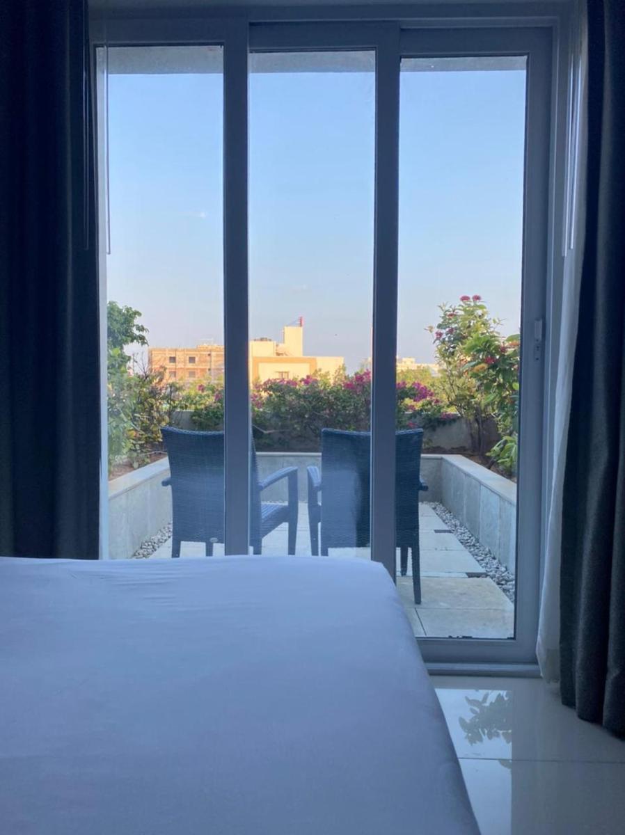a bedroom with a view of a table and chairs through a window at The Residency Towers, Rameswaram in Rāmeswaram
