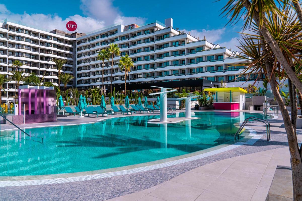 Una piscina con sillas y un gran edificio. en Spring Hotel Bitácora, en Playa de las Américas