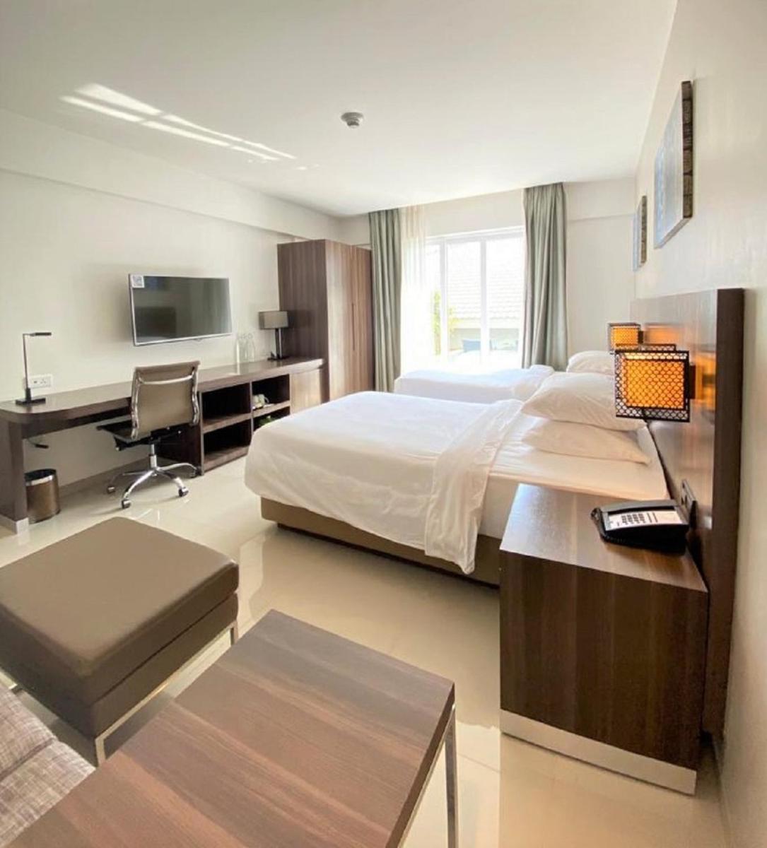 a bedroom with a bed and a desk with a computer at The Residency Towers, Rameswaram in Rāmeswaram