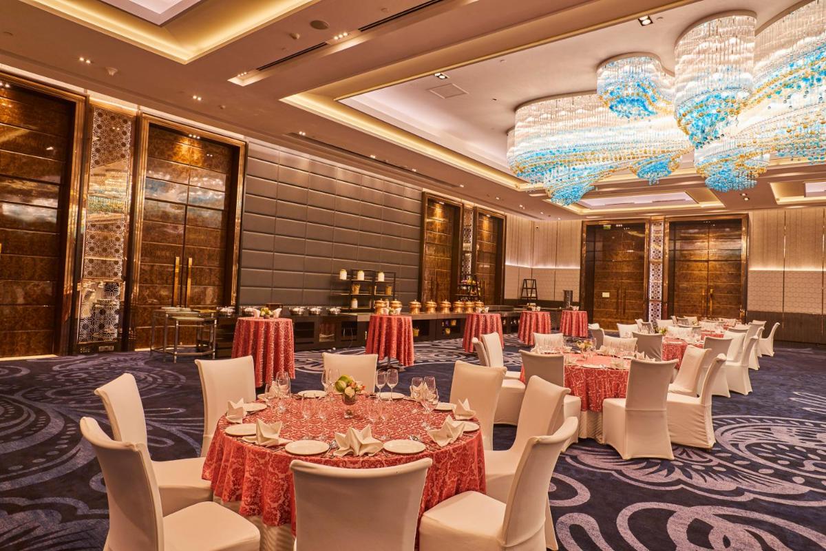 a banquet hall with tables and chairs and chandeliers at Crowne Plaza New Delhi Rohini by IHG in New Delhi a banquet hall with tables and chairs and chandeliers at Crowne Plaza New Delhi Rohini by IHG in New Delhi