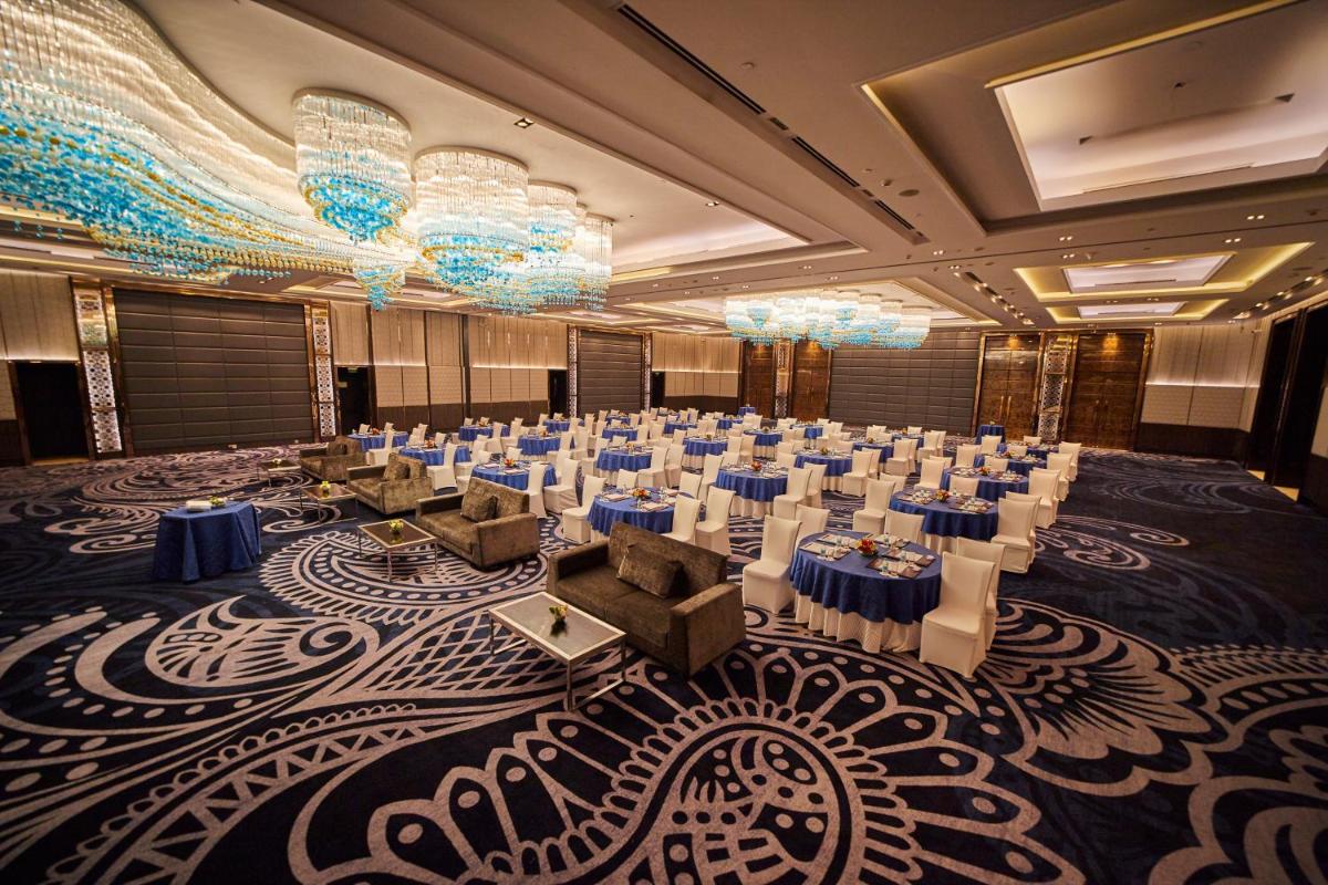 a banquet hall with tables and chairs and chandeliers at Crowne Plaza New Delhi Rohini by IHG in New Delhi a banquet hall with tables and chairs and chandeliers at Crowne Plaza New Delhi Rohini by IHG in New Delhi