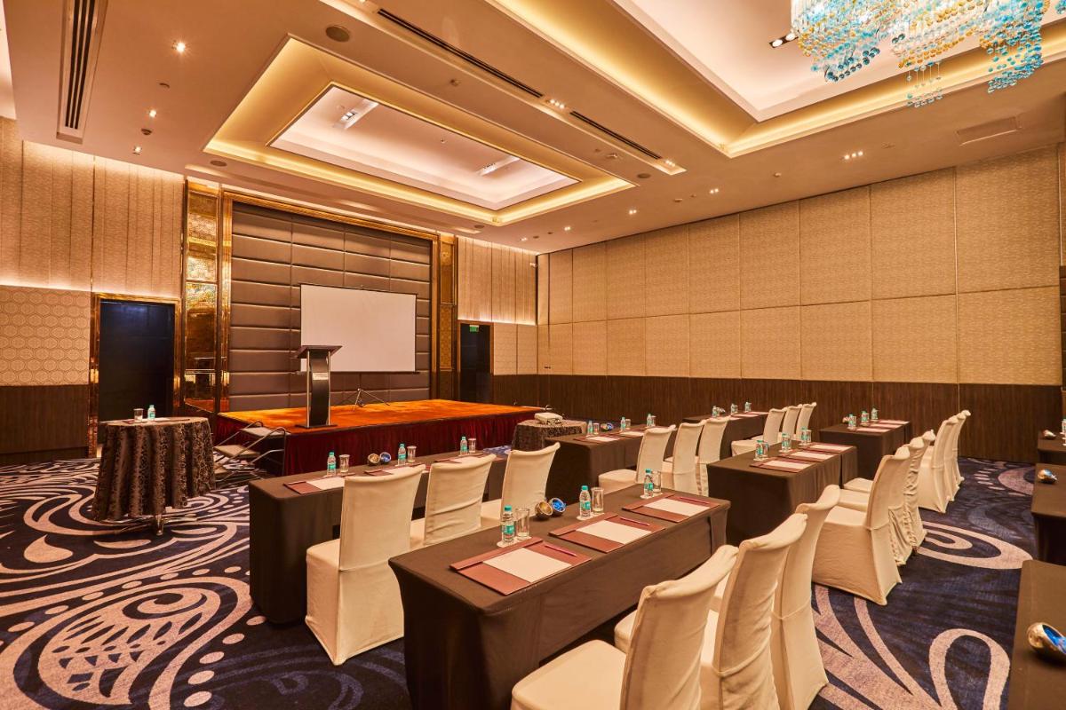 a conference room with tables and chairs and a podium at Crowne Plaza New Delhi Rohini by IHG in New Delhi a conference room with tables and chairs and a podium at Crowne Plaza New Delhi Rohini by IHG in New Delhi