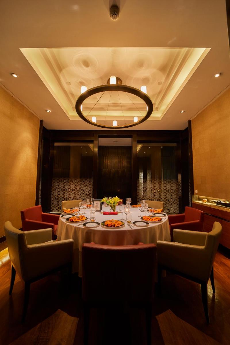 a dining room with a table and chairs and a chandelier at Crowne Plaza New Delhi Rohini by IHG in New Delhi a dining room with a table and chairs and a chandelier at Crowne Plaza New Delhi Rohini by IHG in New Delhi