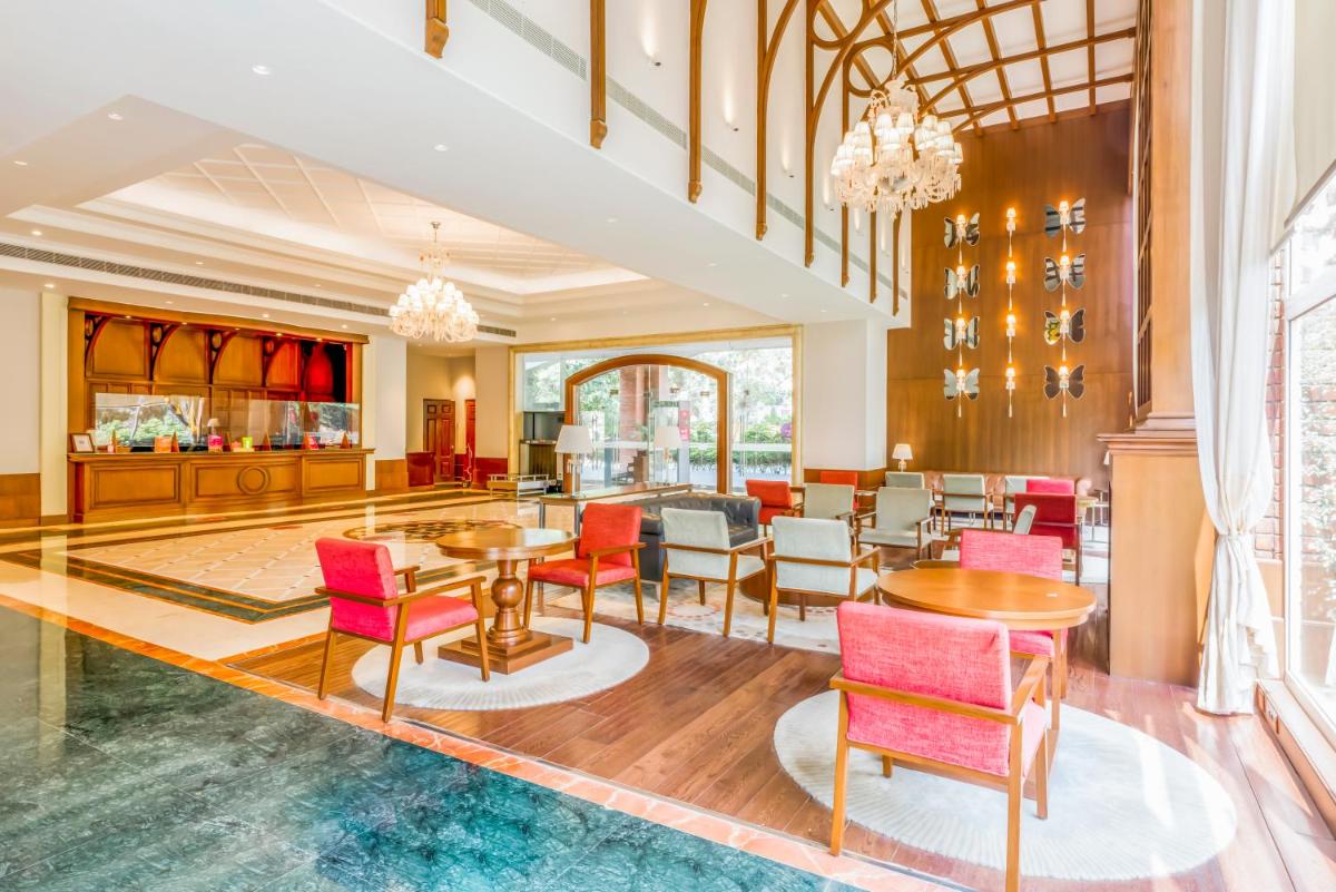 a lobby with tables and chairs in a building at Hotel Royal Orchid Bangalore in Bengaluru