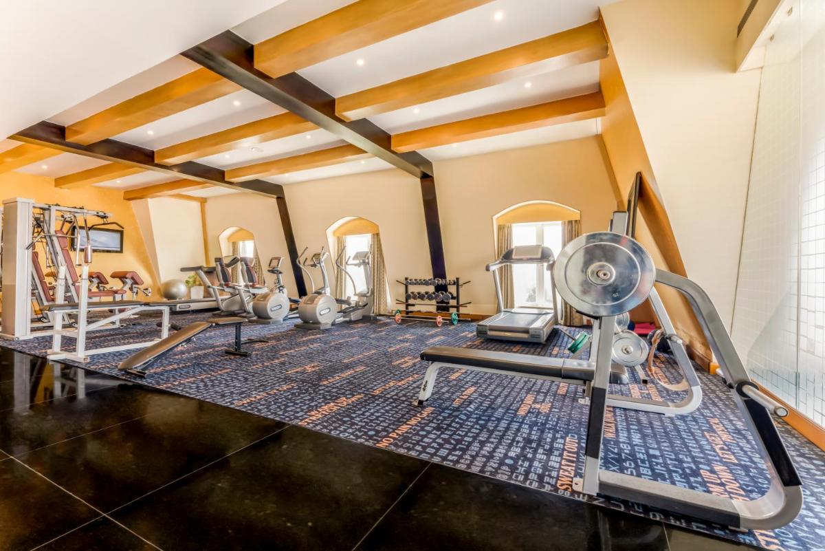 a gym with treadmills and elliptical machines at Hotel Royal Orchid Bangalore in Bengaluru