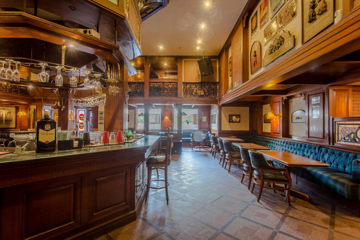 a bar with tables and chairs in a restaurant at Hotel Royal Orchid Bangalore in Bengaluru