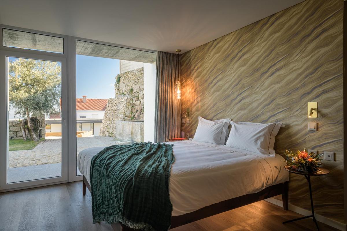 um quarto com uma cama grande e uma janela grande em Pena D'Água Boutique Hotel & Villas na Covilhã mais 35 fotografias