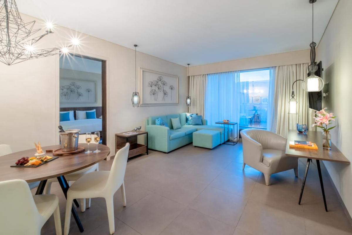 a living room with a table and chairs and a couch at Hyatt Centric Candolim Goa in Calangute a living room with a table and chairs and a couch at Hyatt Centric Candolim Goa in Calangute