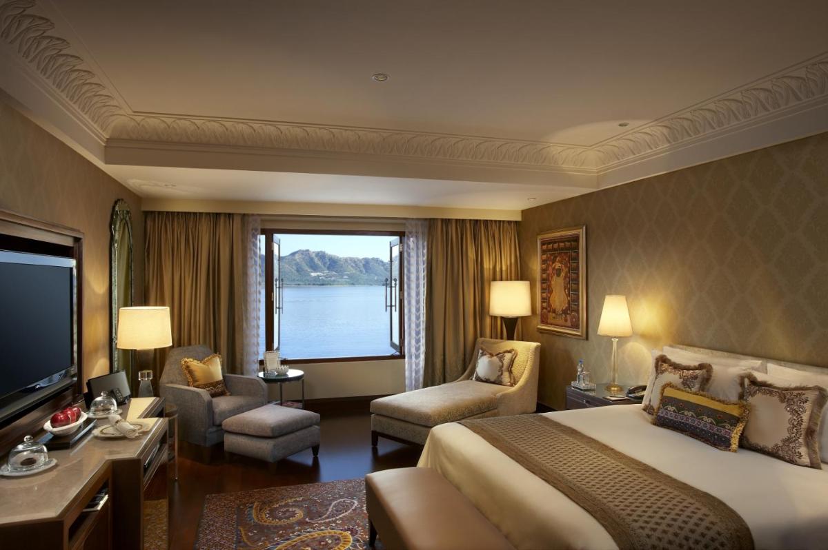 a hotel room with a large bed and a large window at The Leela Palace Udaipur in Udaipur
