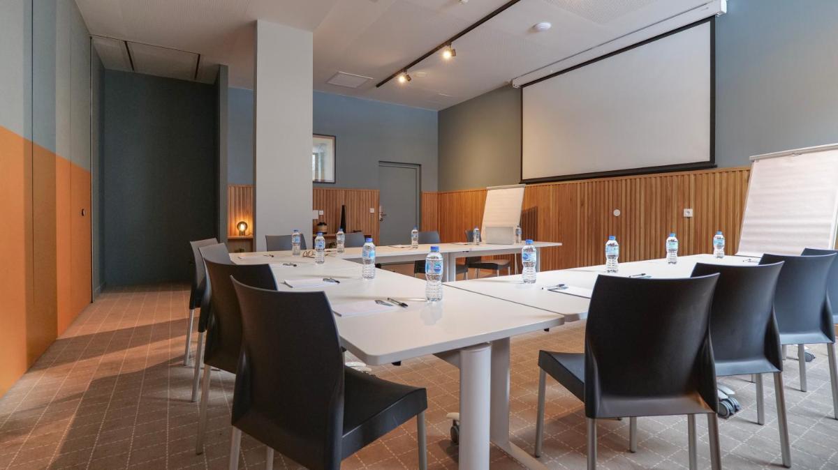 une salle de conférence avec tables et chaises et un écran de projection dans l'établissement Plan B Hotel - Living Chamonix, à Chamonix-Mont-Blanc