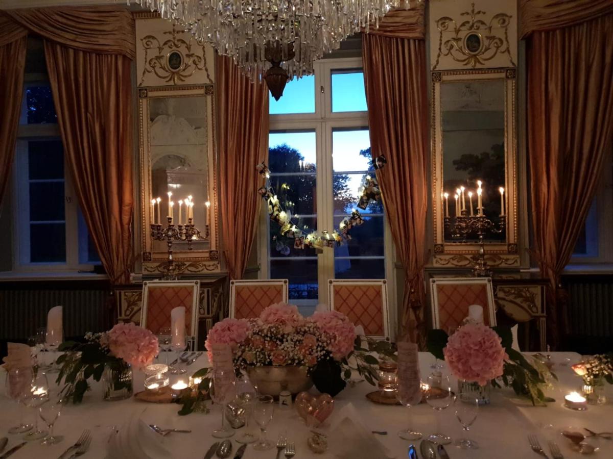 ein Esszimmer mit einem Tisch mit Blumen und einem Kronleuchter in der Unterkunft Herrenhaus Borghorst in Osdorf