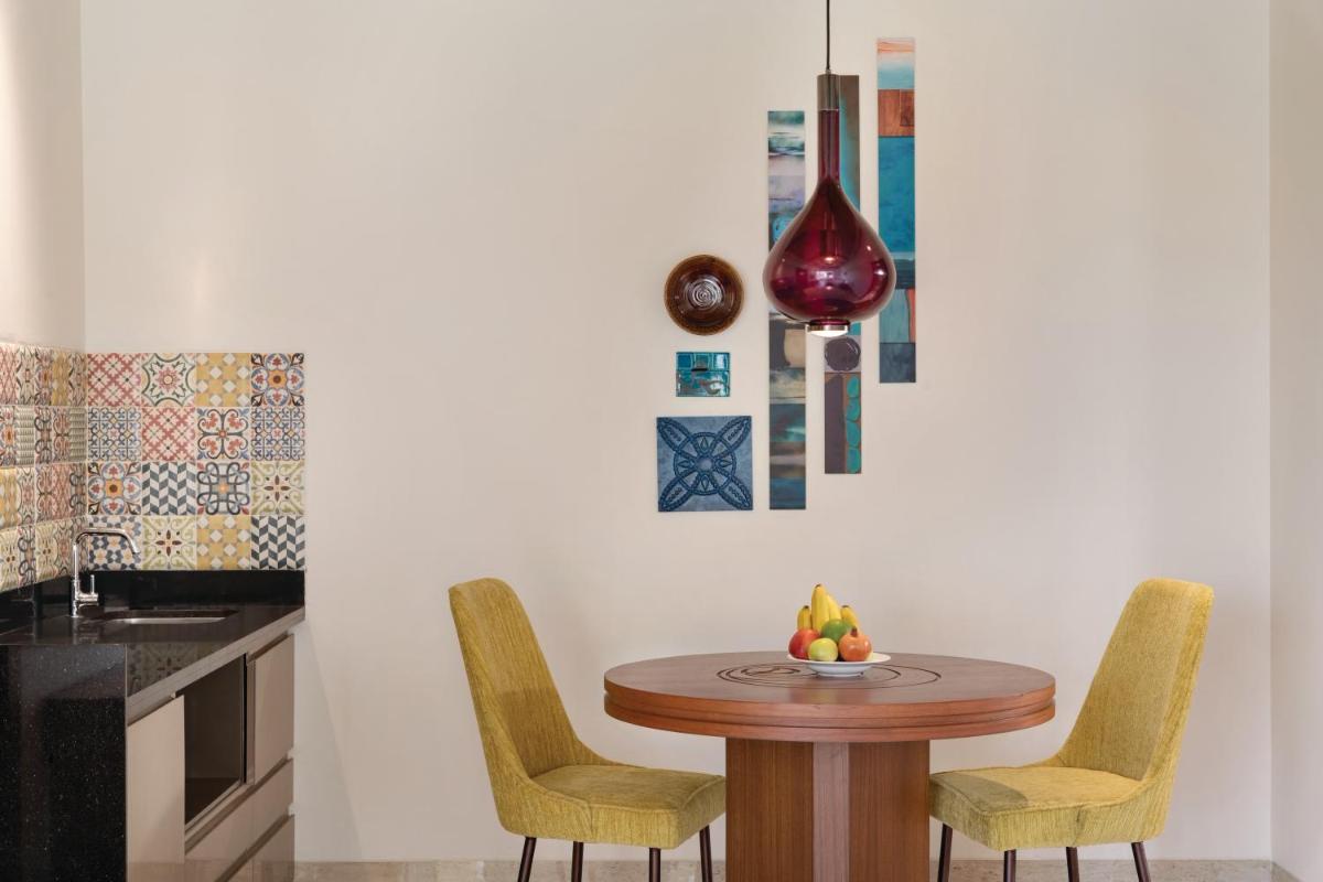 a kitchen with a table with chairs and a vase at Hawthorn Suites by Wyndham Dwarka in Dwarka a kitchen with a table with chairs and a vase at Hawthorn Suites by Wyndham Dwarka in Dwarka