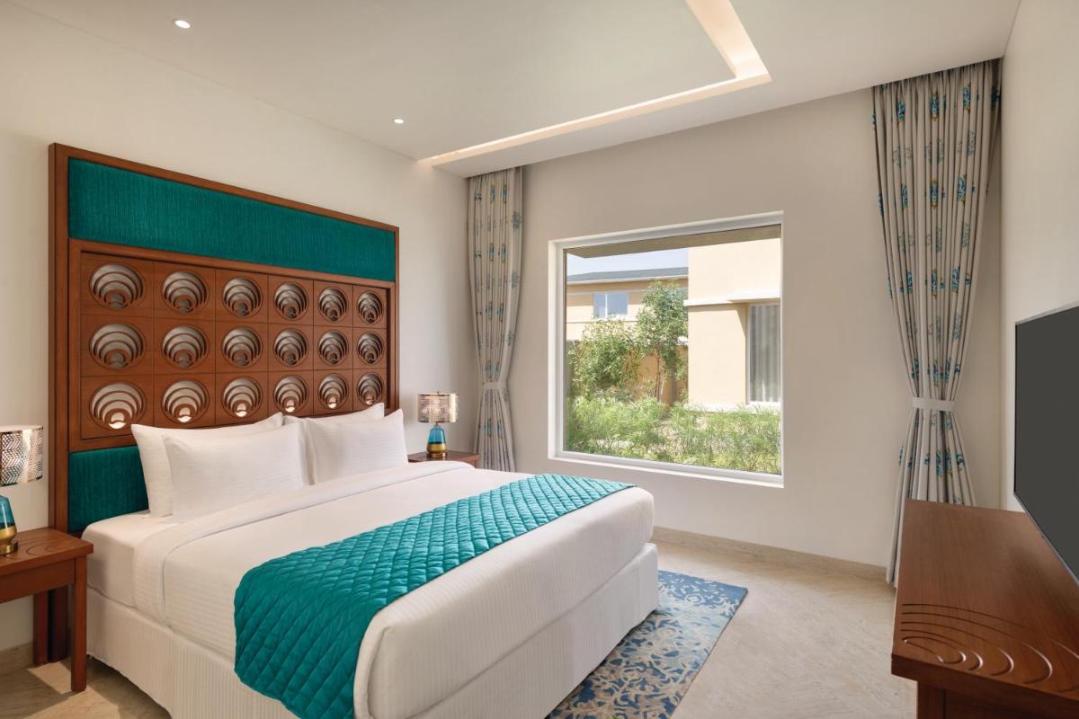 a bedroom with a large bed and a window at Hawthorn Suites by Wyndham Dwarka in Dwarka a bedroom with a large bed and a window at Hawthorn Suites by Wyndham Dwarka in Dwarka