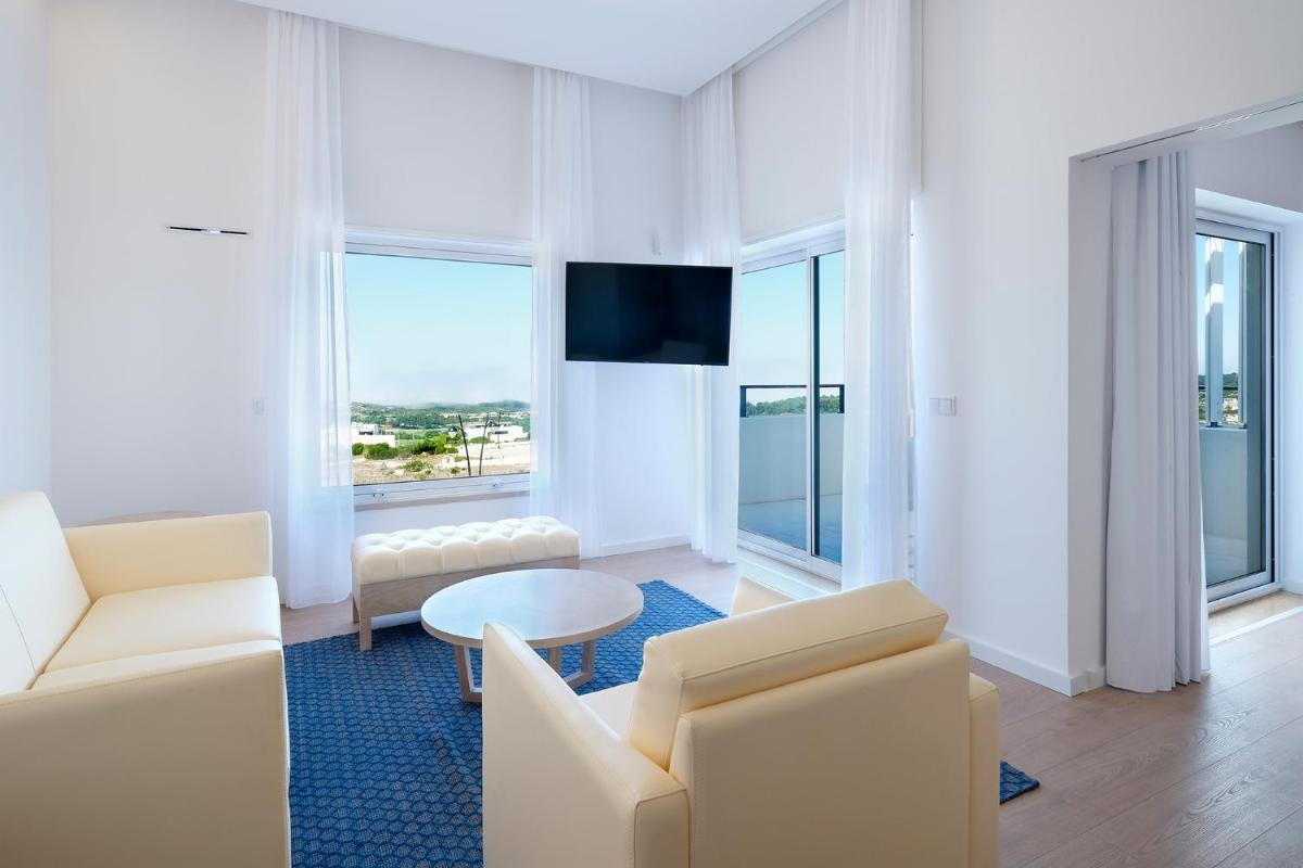 uma sala de estar com mobiliário branco e janelas grandes em Royal Obidos Scenic Resort em Praia del Rei