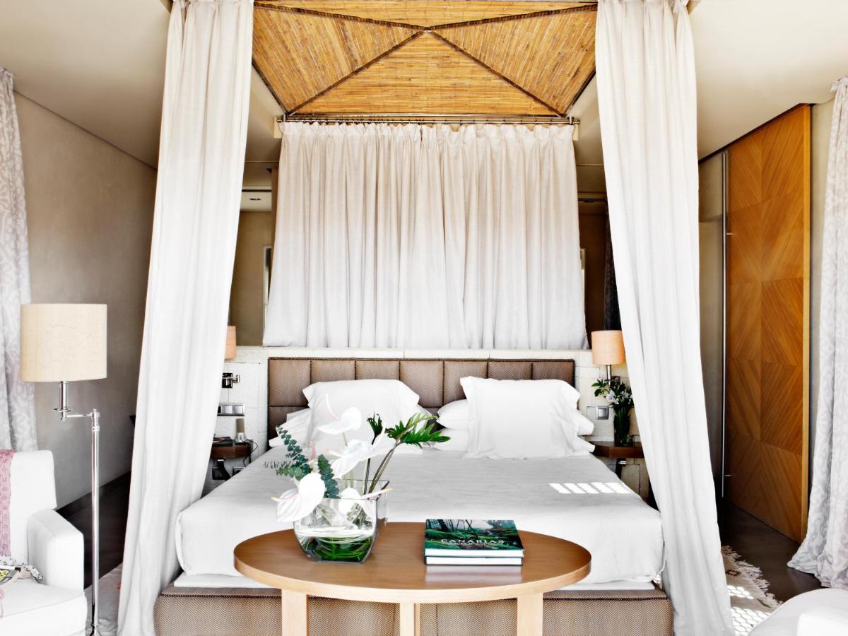 1 dormitorio con cama con dosel y mesa en The Villas at Bahia del Duque, en Adeje