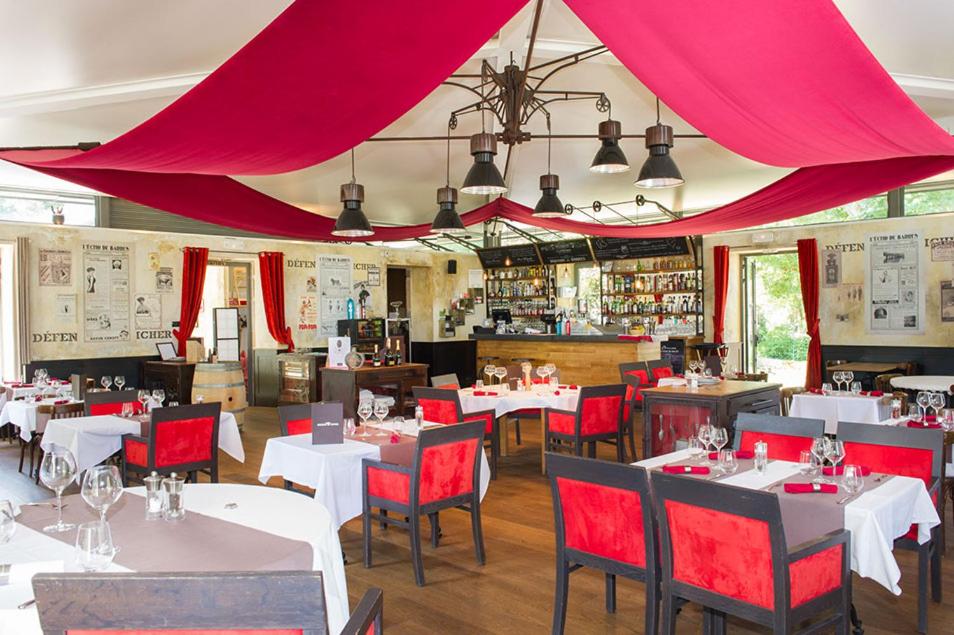 un restaurant avec des tables blanches et des chaises rouges dans l'établissement Domaine De Barres, à Langogne