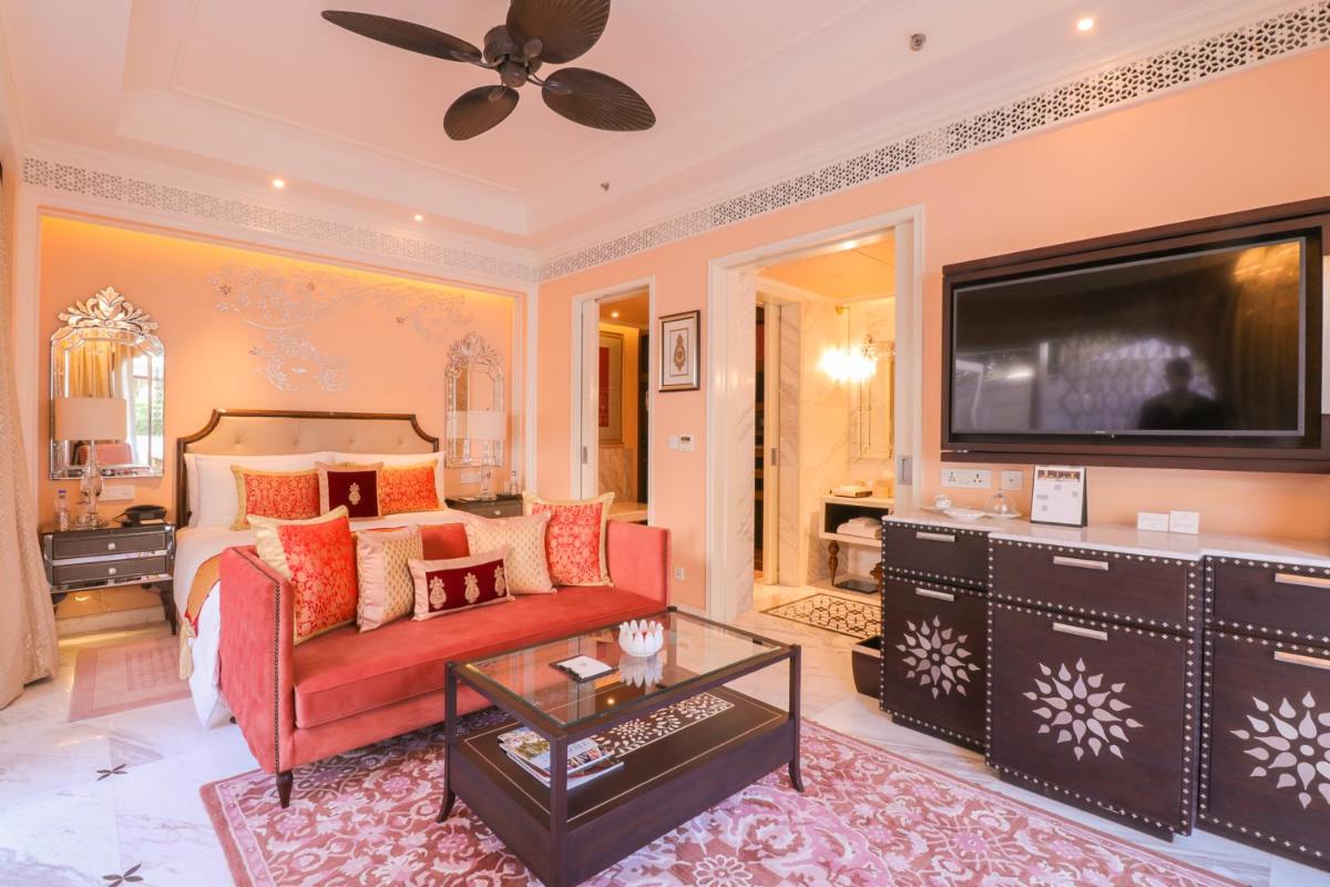 a living room with a red couch and a television at The Leela Palace Jaipur in Jaipur