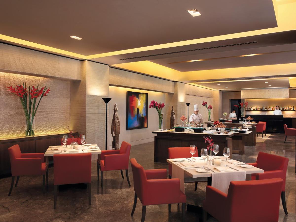a restaurant with tables and chairs and a chef in the kitchen at The Oberoi Mumbai in Mumbai
