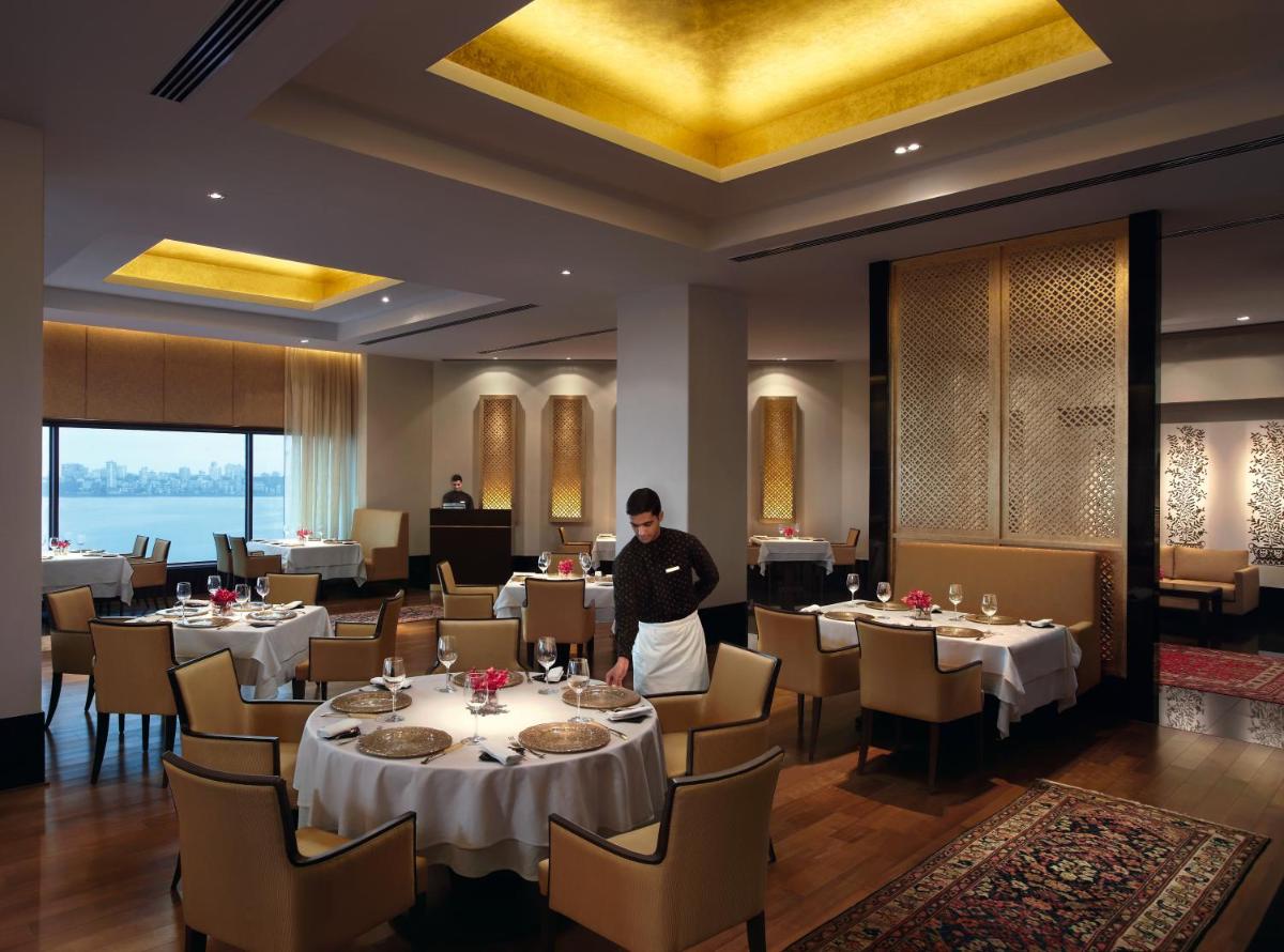 a man standing in a dining room with tables at The Oberoi Mumbai in Mumbai