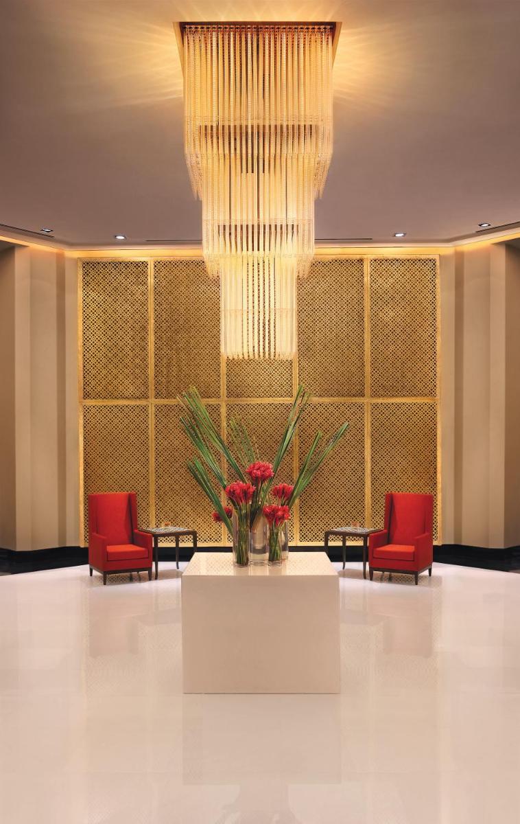 a lobby with red chairs and a large chandelier at The Oberoi Mumbai in Mumbai