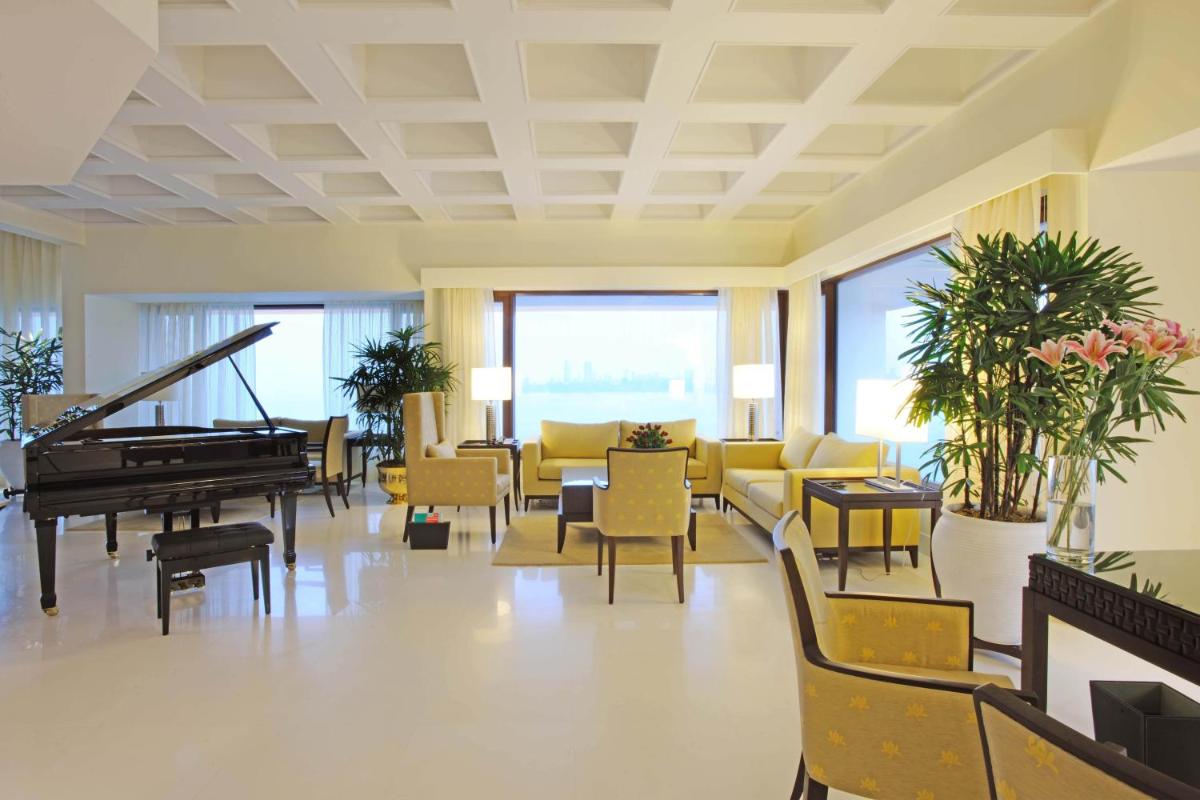 a lobby with a piano and chairs and tables at The Oberoi Mumbai in Mumbai