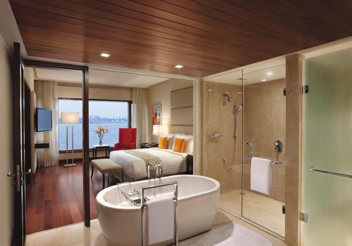 a bathroom with a tub and a bedroom with a bed at The Oberoi Mumbai in Mumbai