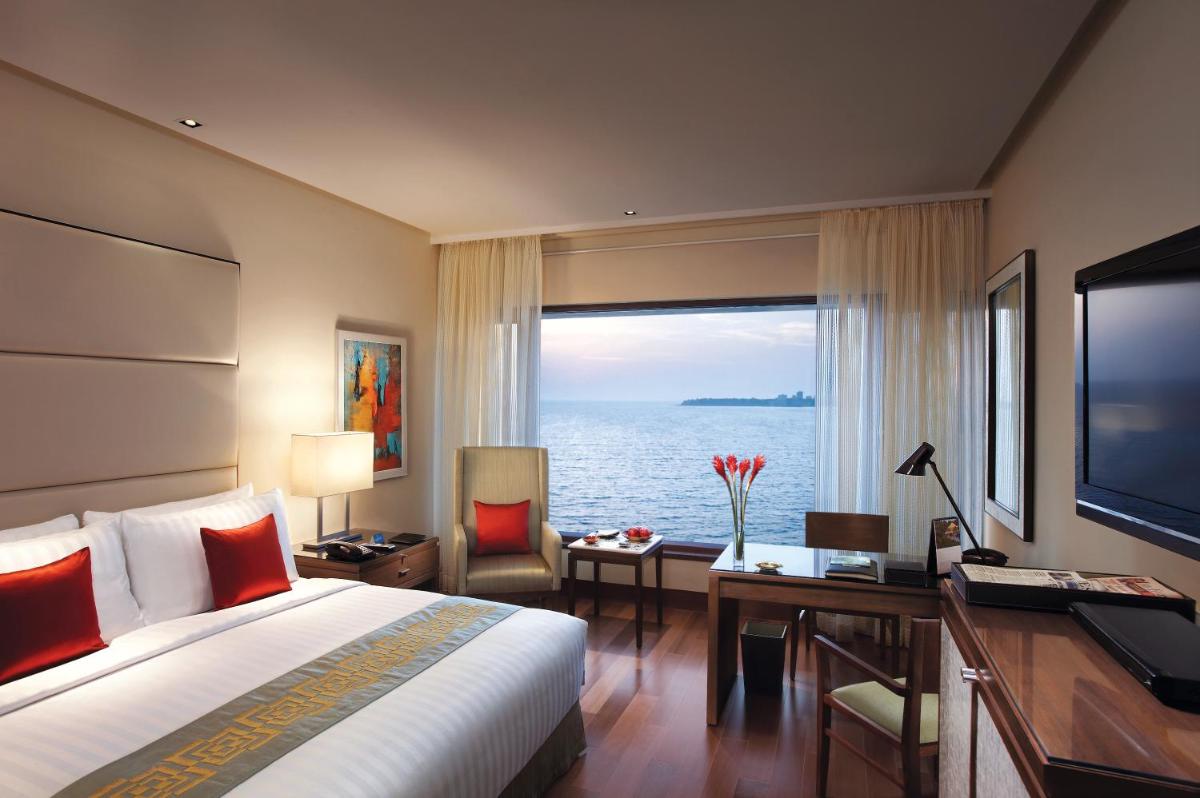a hotel room with a bed and a desk and a large window at The Oberoi Mumbai in Mumbai