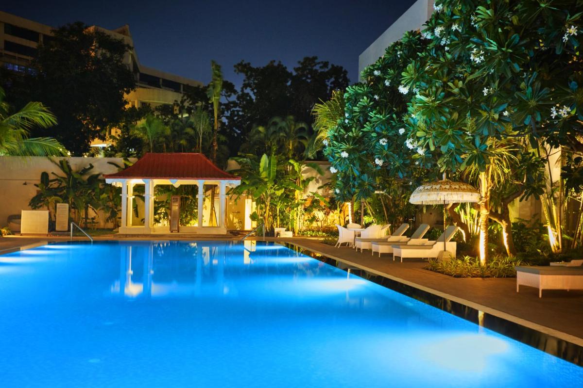 a large swimming pool with chairs and a gazebo at Taj Connemara, Chennai in Chennai