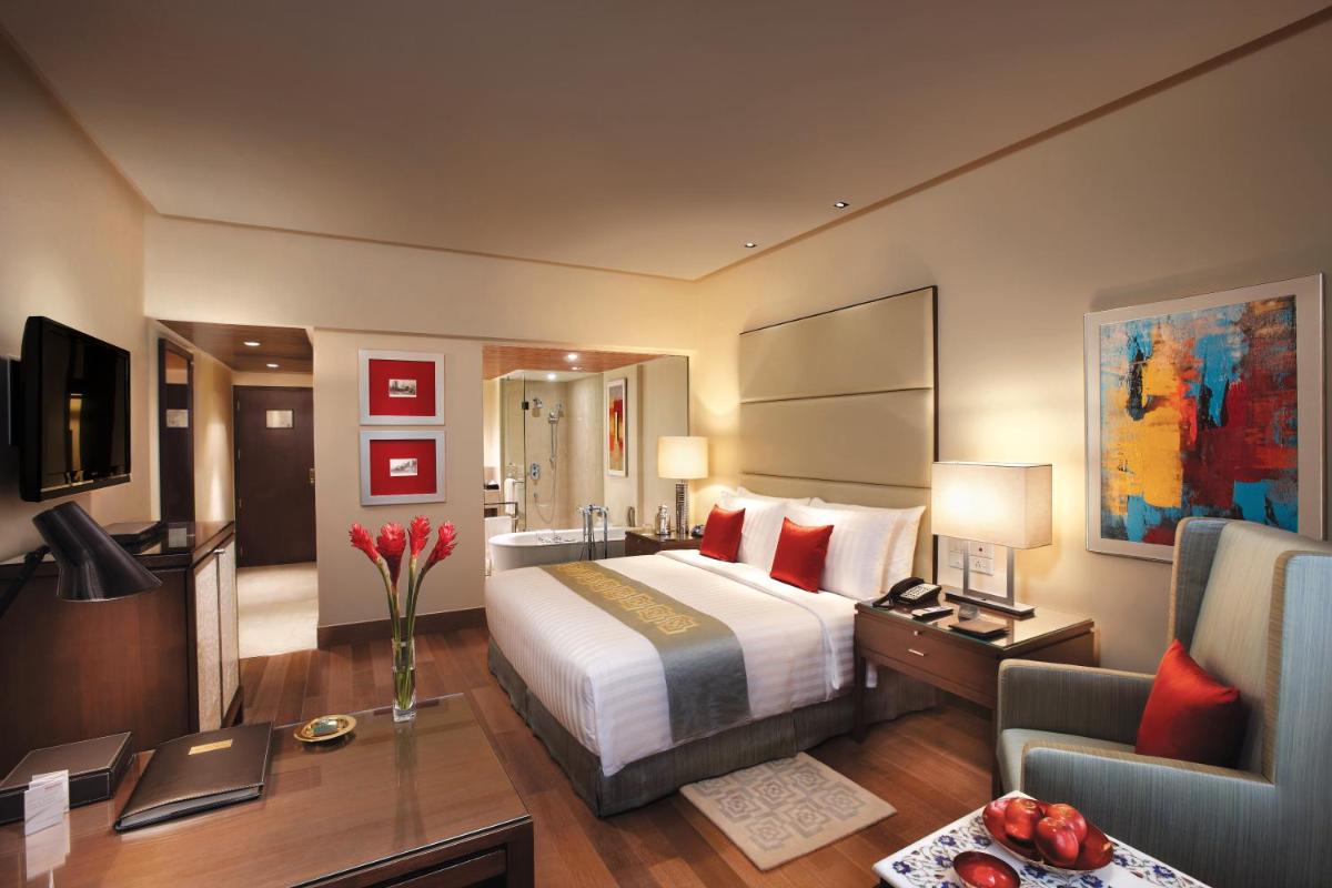 a hotel room with a large bed and a desk at The Oberoi Mumbai in Mumbai
