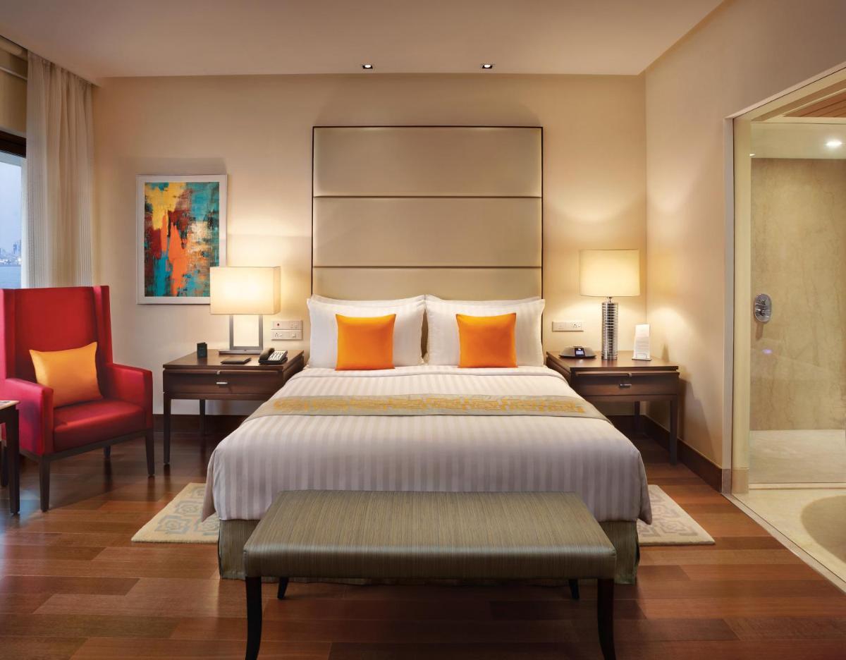 a bedroom with a large bed and a red chair at The Oberoi Mumbai in Mumbai