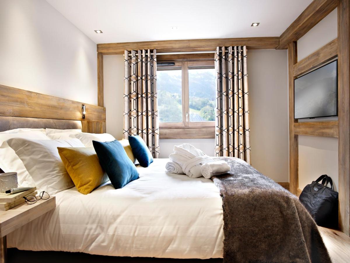 une chambre avec un lit blanc avec des oreillers et une fenêtre dans l'établissement MGM Hôtels & Résidences - Résidence Chalets Laska, aux Contamines-Montjoie