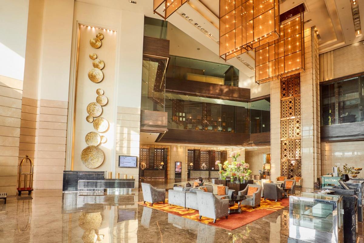 a lobby of a hotel with tables and chairs at Crowne Plaza New Delhi Rohini by IHG in New Delhi a lobby of a hotel with tables and chairs at Crowne Plaza New Delhi Rohini by IHG in New Delhi